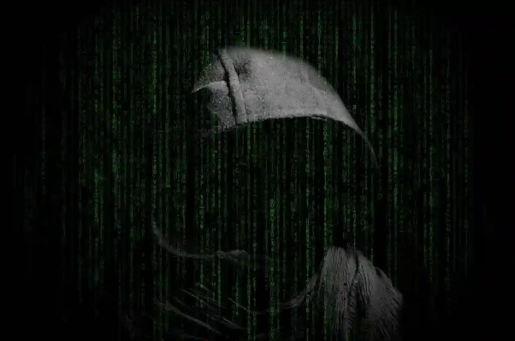 An anonymous hooded figure is obscured by falling green "Matrix-style" code, representing a cyber hacker or security threat.
